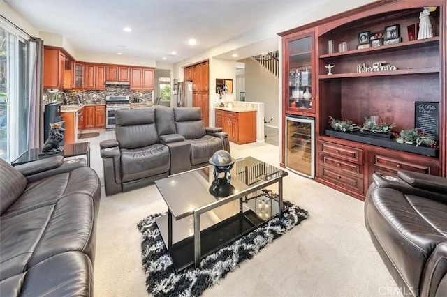 living room featuring wine cooler, light carpet, plenty of natural light, and indoor wet bar