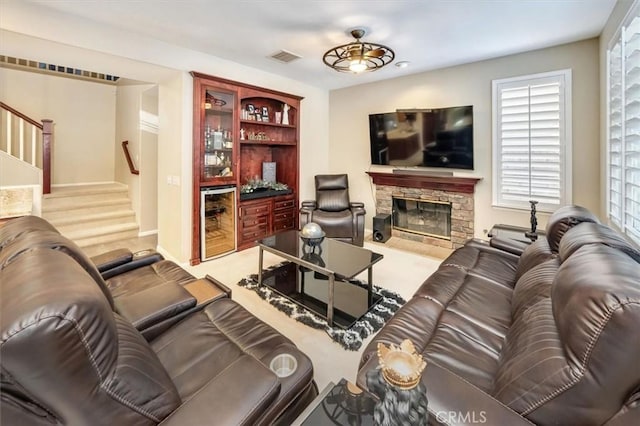 living room featuring wine cooler, a fireplace, bar area, and carpet flooring