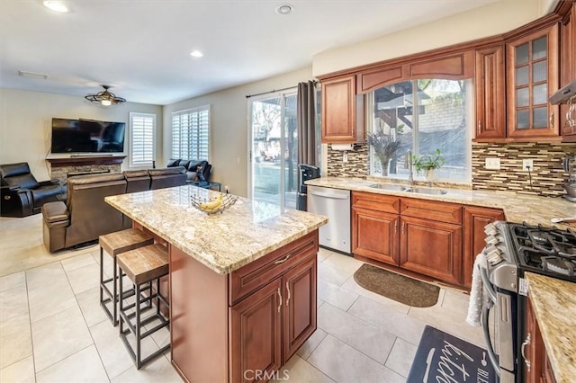 kitchen featuring sink, stainless steel appliances, a breakfast bar, and light stone countertops