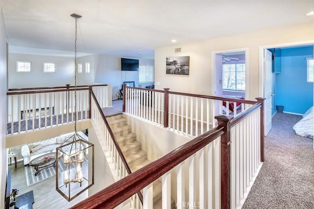 hall with light colored carpet and a chandelier