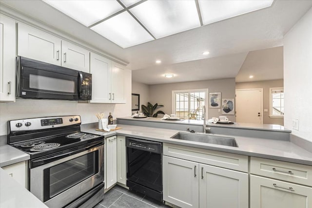 kitchen with dark tile patterned floors, sink, kitchen peninsula, and black appliances