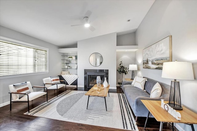 living room featuring ceiling fan, dark wood-type flooring, lofted ceiling, and a tiled fireplace