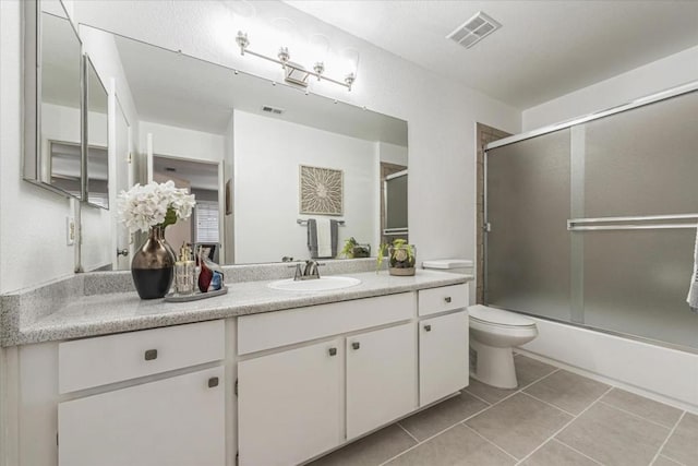 full bathroom featuring combined bath / shower with glass door, vanity, toilet, and tile patterned flooring