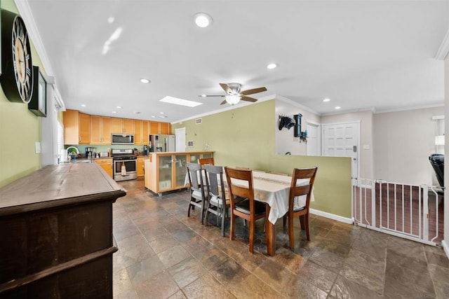 dining space with ceiling fan, sink, a skylight, and crown molding