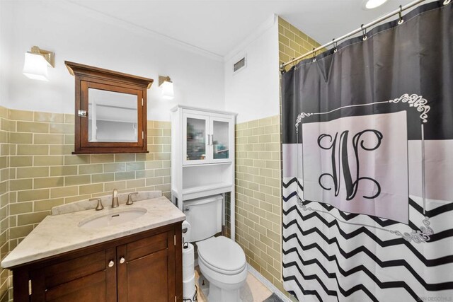 bathroom featuring tile walls, toilet, vanity, and ornamental molding