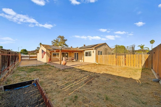 rear view of house with a patio area and solar panels