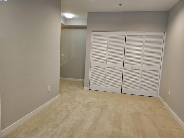 unfurnished bedroom featuring a closet and light carpet