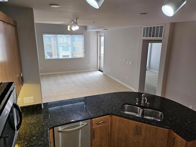 kitchen with dark stone countertops, dishwasher, and sink