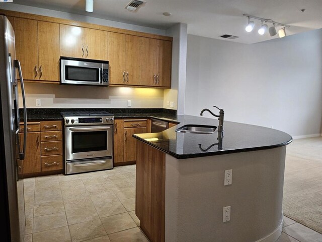 kitchen with dark stone counters, sink, stainless steel appliances, and light tile patterned flooring