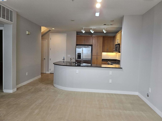 kitchen featuring light carpet, kitchen peninsula, stainless steel fridge, track lighting, and sink