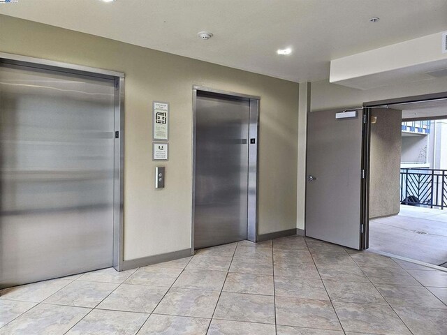 hallway featuring light tile patterned flooring and elevator