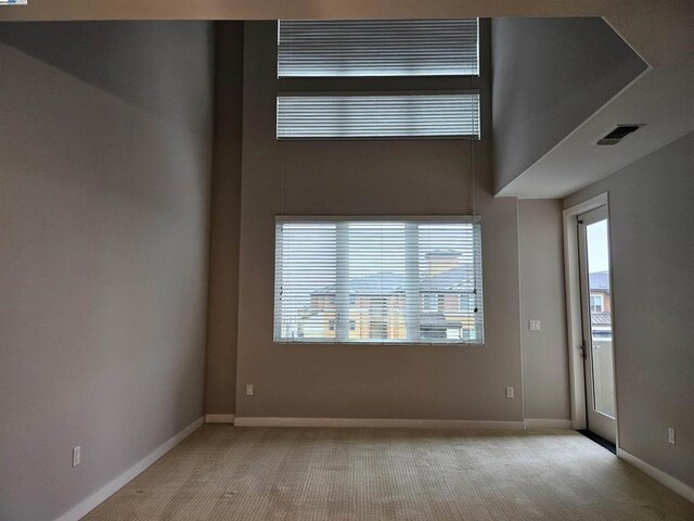 unfurnished room featuring light carpet and a high ceiling