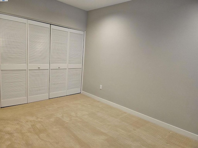 unfurnished bedroom featuring light colored carpet and a closet