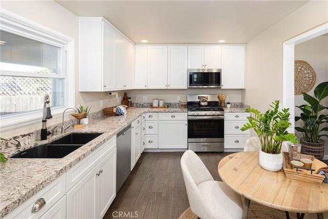 kitchen featuring light stone countertops, appliances with stainless steel finishes, white cabinetry, and sink