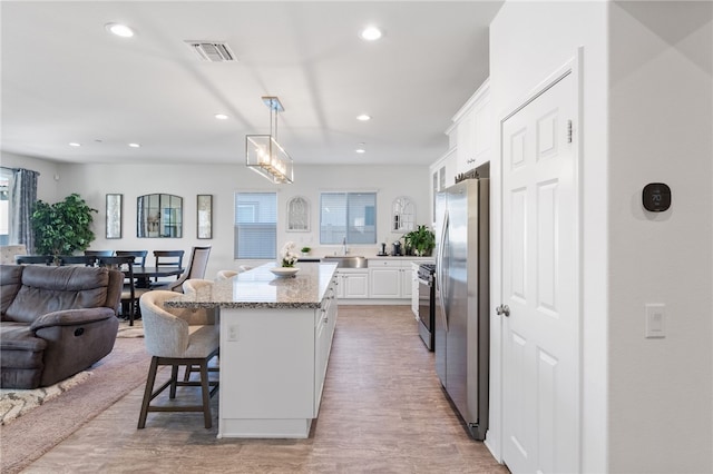 kitchen with pendant lighting, white cabinets, a kitchen breakfast bar, appliances with stainless steel finishes, and a kitchen island