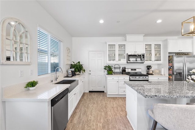 kitchen featuring sink, light wood-type flooring, a kitchen bar, white cabinetry, and stainless steel appliances