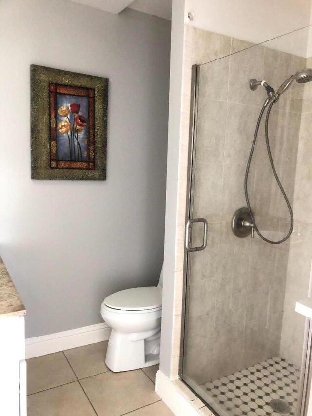 bathroom with toilet, a shower with door, vanity, and tile patterned flooring