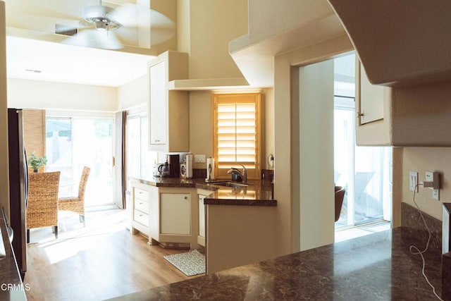 kitchen featuring stainless steel refrigerator, white cabinetry, sink, and light wood-type flooring