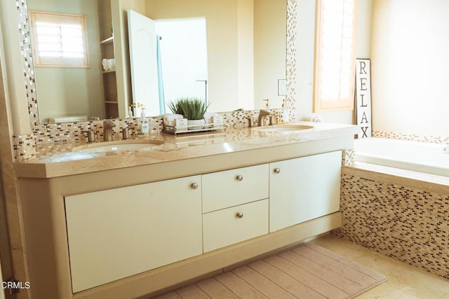 bathroom with tile patterned floors, vanity, and a relaxing tiled tub