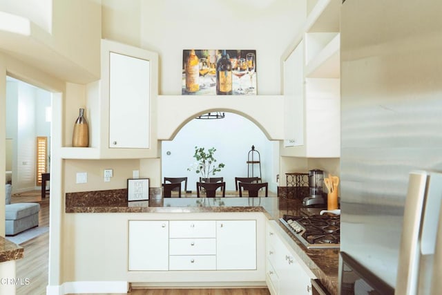 kitchen with dark stone countertops, white cabinetry, light hardwood / wood-style flooring, and appliances with stainless steel finishes