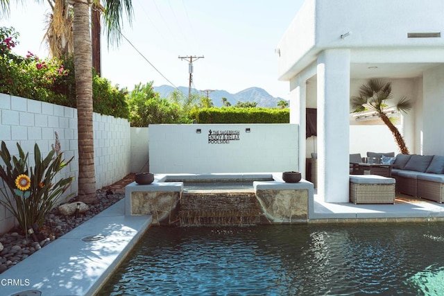 view of pool with outdoor lounge area, a mountain view, and a patio