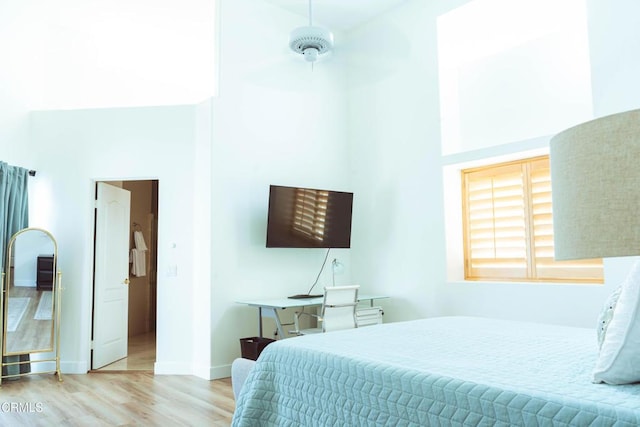 bedroom featuring a high ceiling and light hardwood / wood-style flooring