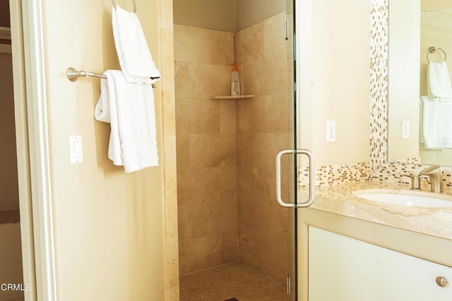 bathroom featuring decorative backsplash, vanity, and a shower with door