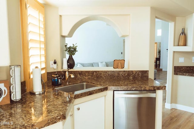 kitchen featuring sink, light hardwood / wood-style flooring, stainless steel dishwasher, white cabinetry, and kitchen peninsula