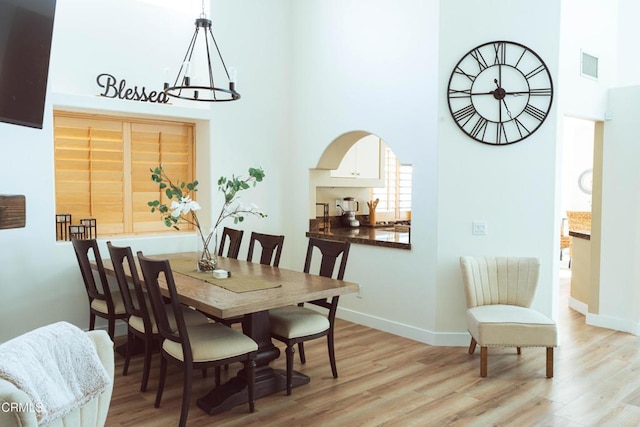 dining space with a notable chandelier and light hardwood / wood-style flooring