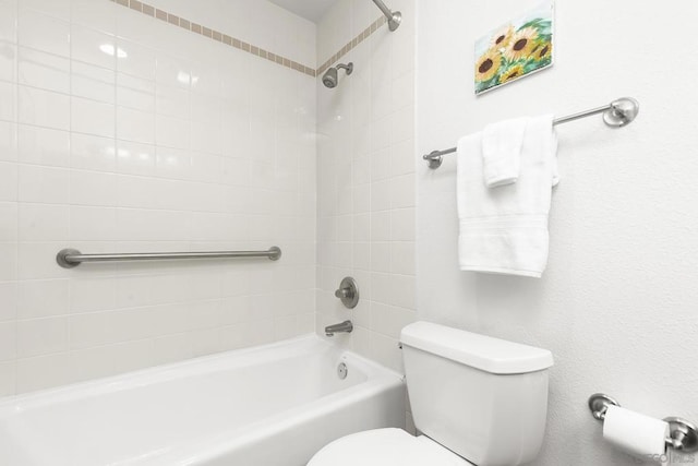 bathroom featuring tiled shower / bath combo and toilet