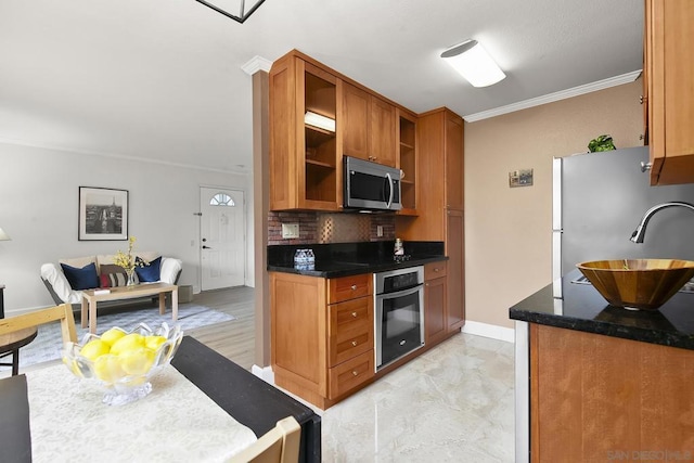 kitchen featuring dark stone countertops, ornamental molding, appliances with stainless steel finishes, and backsplash