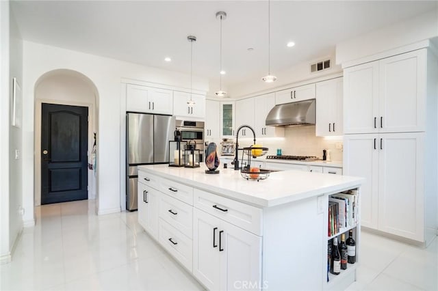 kitchen with hanging light fixtures, an island with sink, stainless steel appliances, light tile patterned floors, and white cabinetry