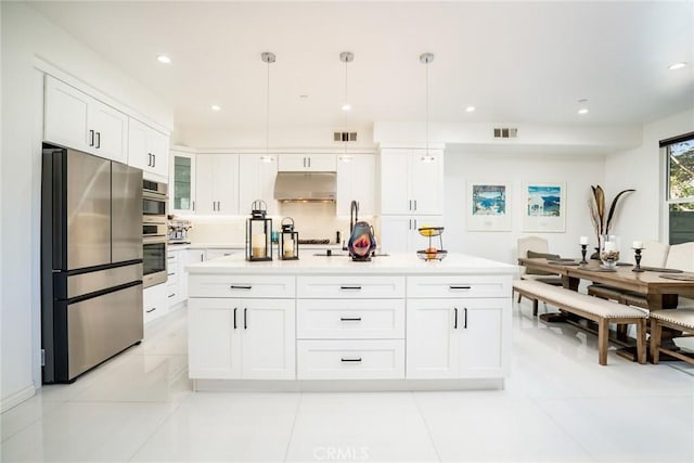 kitchen with decorative light fixtures, stainless steel appliances, light tile patterned floors, a kitchen island with sink, and white cabinetry