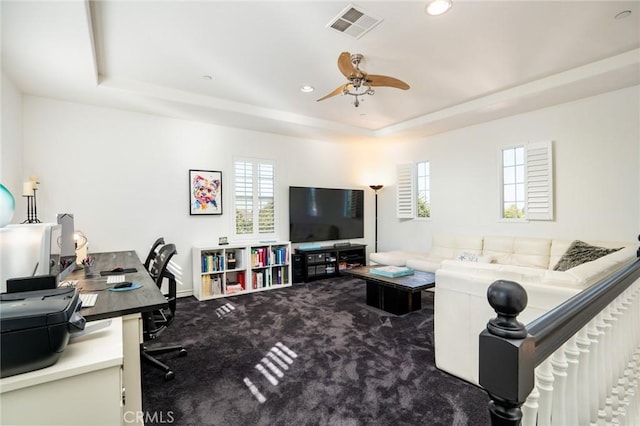 living room featuring ceiling fan, a tray ceiling, and carpet flooring