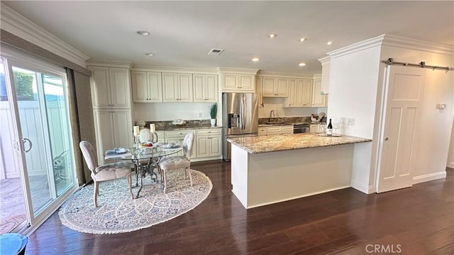 kitchen with light stone countertops, dark wood-type flooring, stainless steel refrigerator with ice dispenser, kitchen peninsula, and crown molding