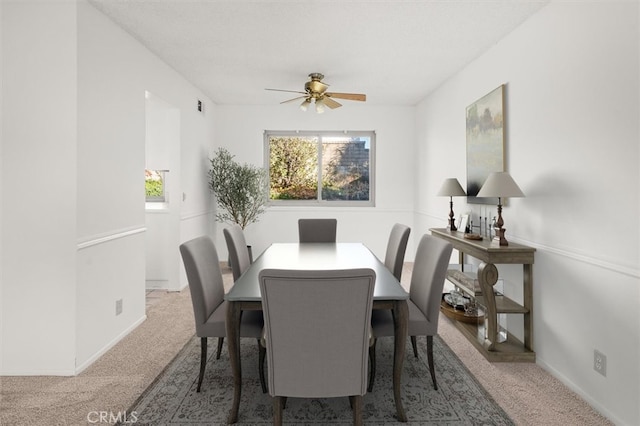 carpeted dining area with ceiling fan