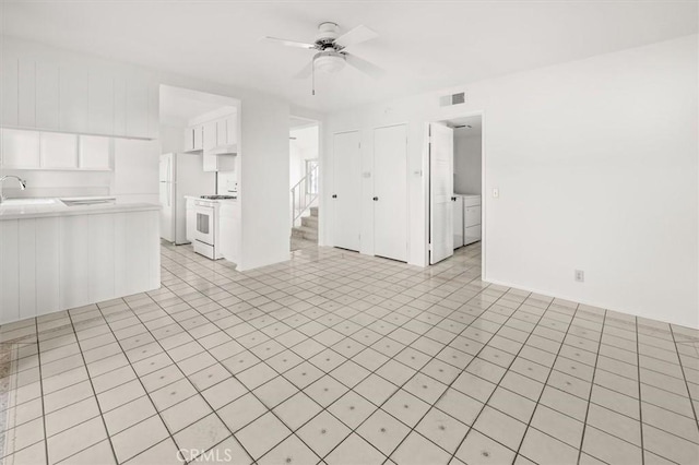 unfurnished living room featuring washer / clothes dryer, ceiling fan, and sink