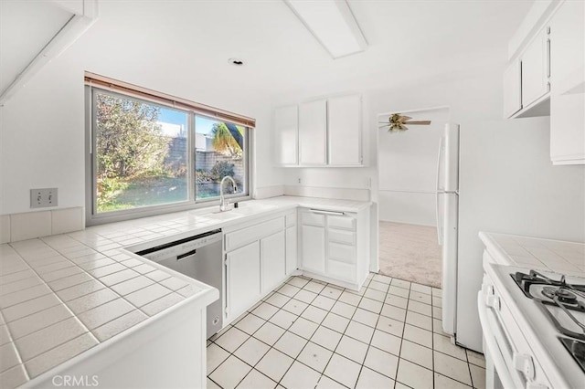 kitchen with stainless steel dishwasher, white cabinetry, sink, and tile countertops