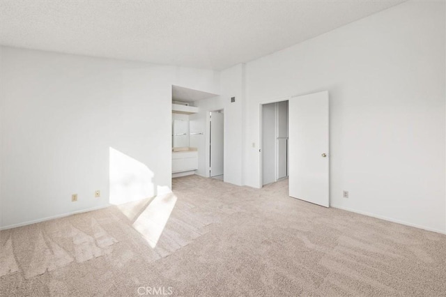 unfurnished bedroom featuring ensuite bathroom and light colored carpet