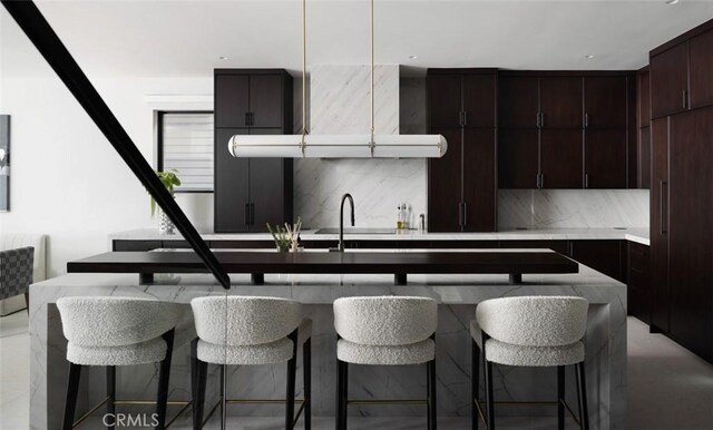 kitchen with a center island, decorative backsplash, a kitchen bar, sink, and dark brown cabinets