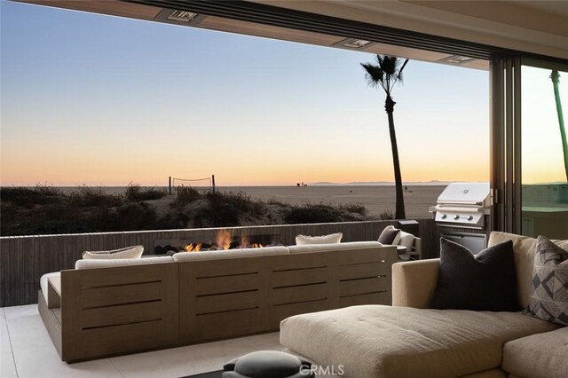 patio terrace at dusk featuring area for grilling, outdoor lounge area, and a water view