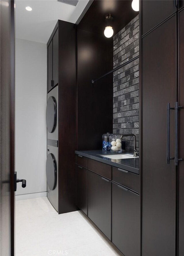 clothes washing area with sink and stacked washer and dryer