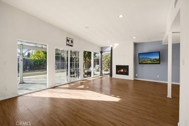 unfurnished living room with french doors, lofted ceiling, a fireplace, and dark hardwood / wood-style floors