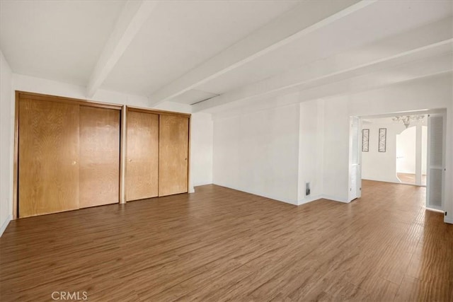 interior space featuring two closets, dark hardwood / wood-style flooring, and beam ceiling