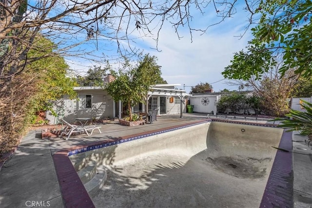 rear view of house featuring a pergola, an empty pool, and a patio