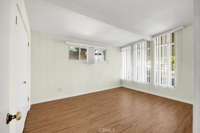 spare room featuring beam ceiling and hardwood / wood-style flooring