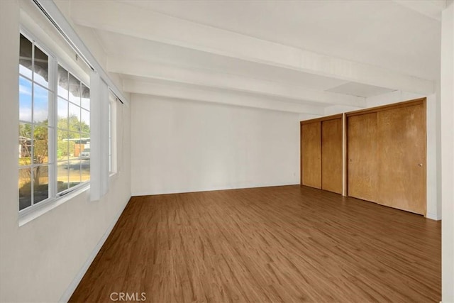 empty room with dark hardwood / wood-style flooring and beamed ceiling