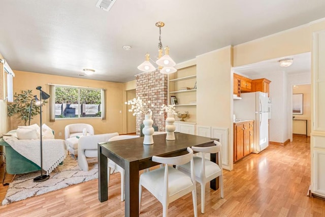 dining area featuring an inviting chandelier, built in features, and light hardwood / wood-style flooring