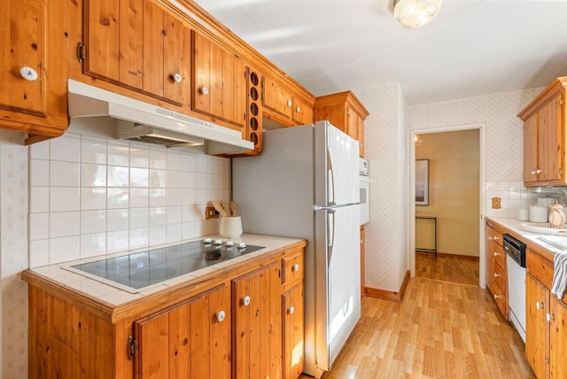 kitchen featuring tasteful backsplash, white appliances, tile countertops, and light wood-type flooring