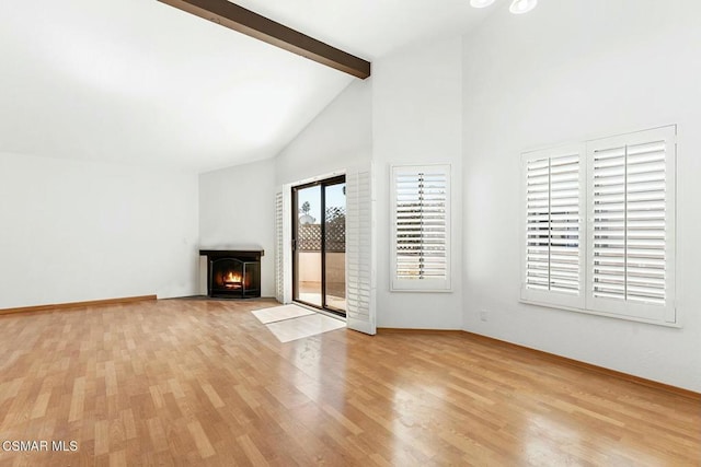 unfurnished living room featuring high vaulted ceiling, beamed ceiling, and light wood-type flooring